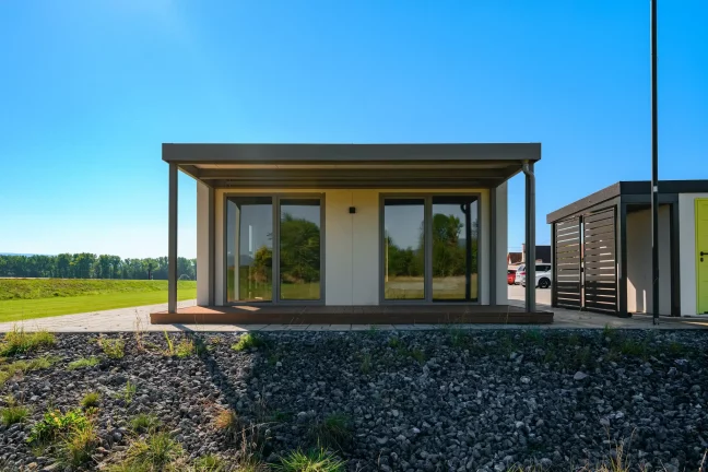 Tiny house spredu s krytou drevenou terasou a posuvnými presklenými dverami