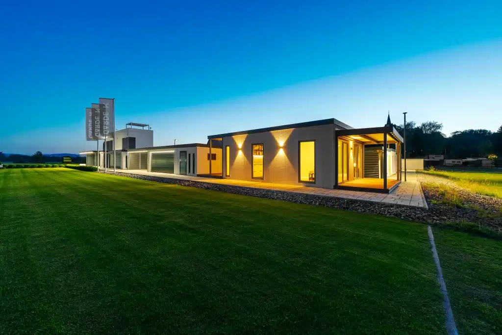 Osvetlený tiny house za súmraku, pohľad z diaľky cez trávnik