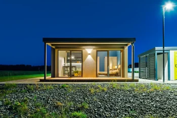 Tiny house spredu večer s osvetlenou krytou terasou